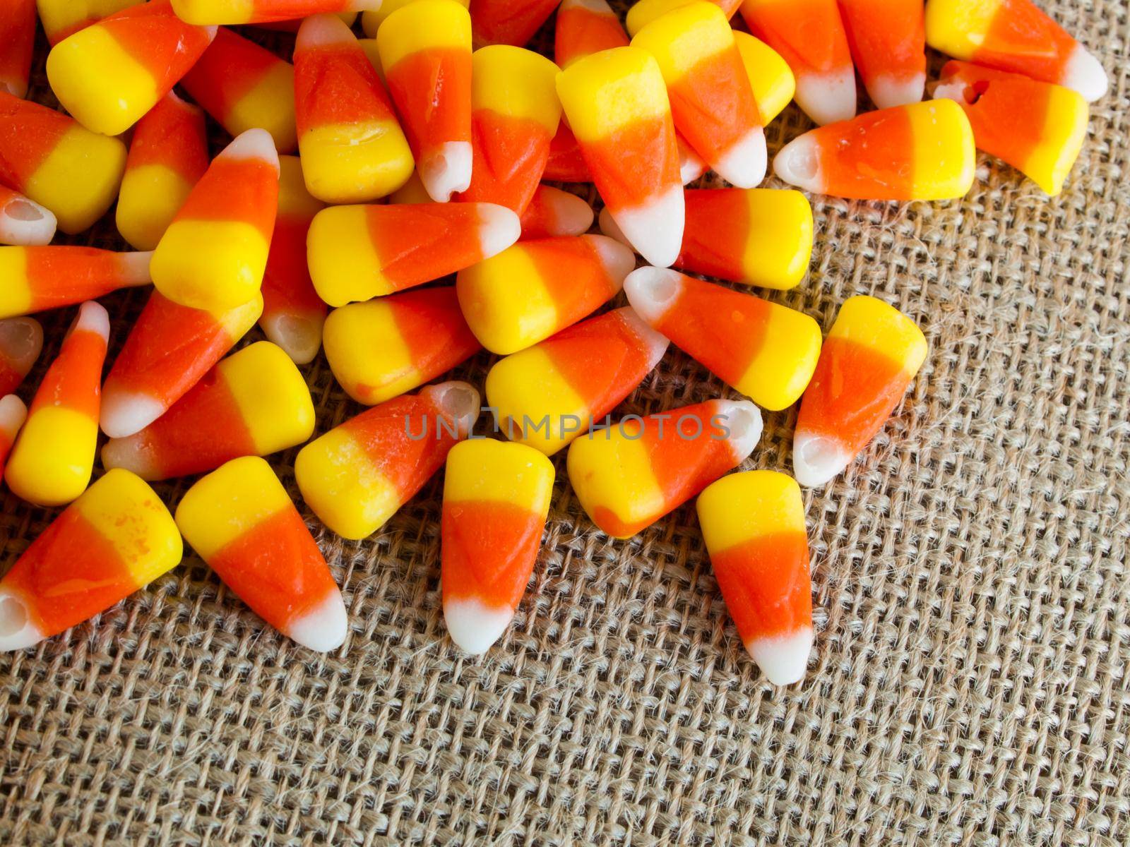 Traditional Halloween candies candy corn on burlap fabric.