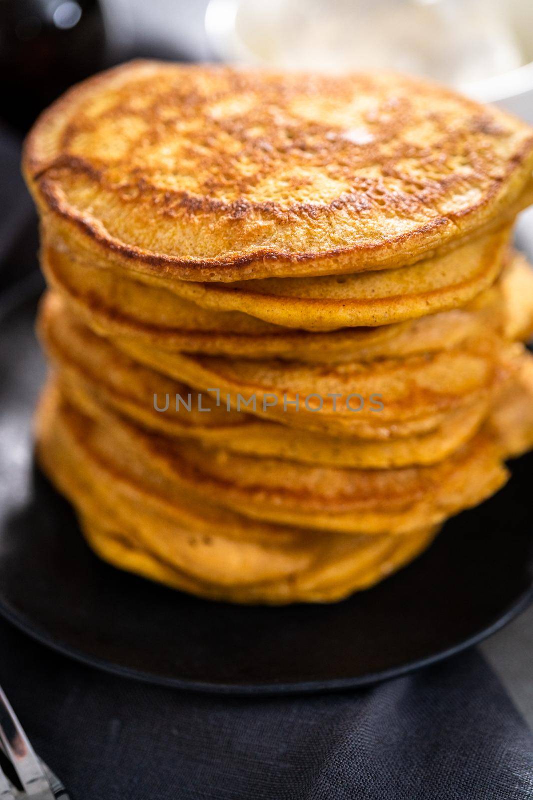 Stack of fresh pumpkin pancakes on a black plate.