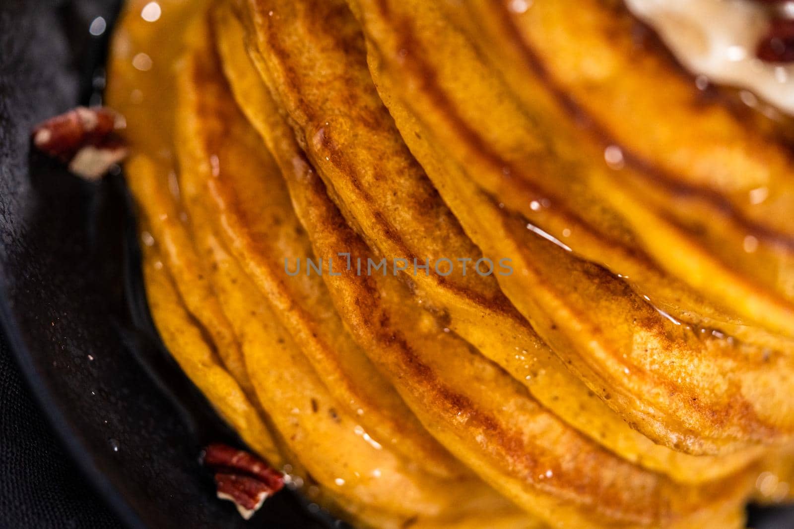 Stack of fresh pumpkin pancakes on a black plate.