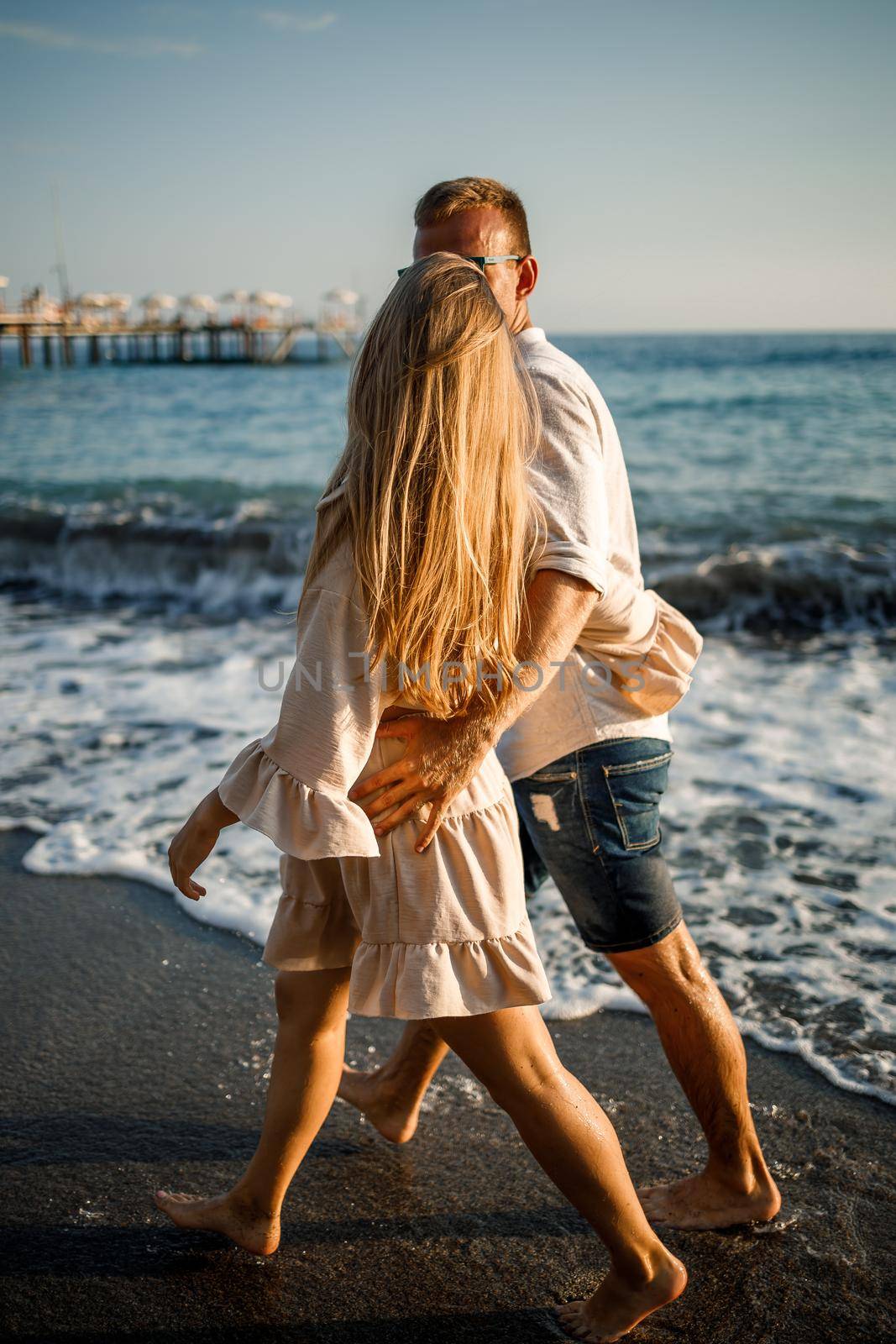 romantic young couple in love together on the sand walks along the beach of the Mediterranean sea. Summer vacation in a warm country. by Dmitrytph