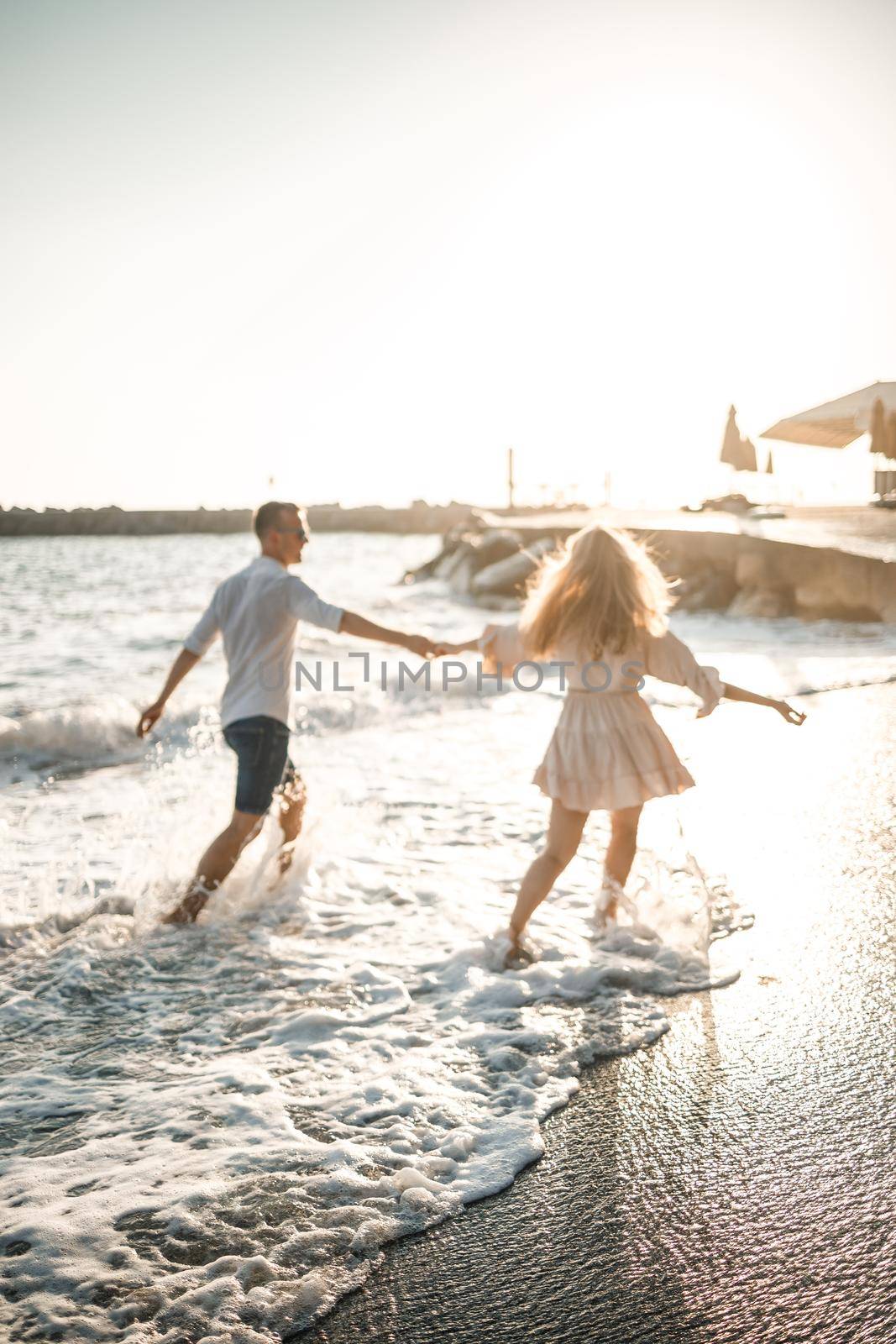 A couple in love is walking on the beach near the sea. Young family at sunset by the mediterranean sea. Summer vacation concept