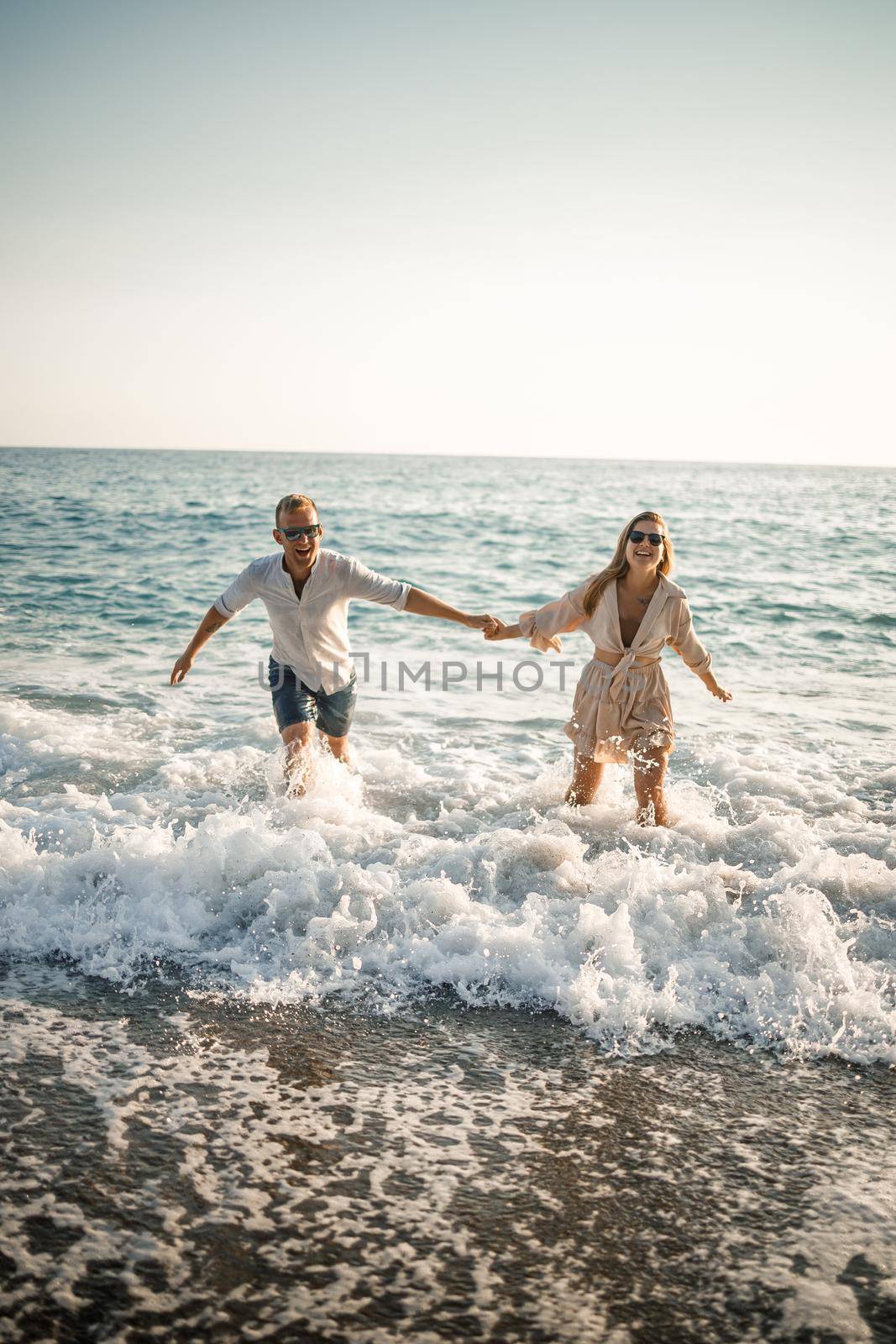 Happy couple by the sea. Honeymoon lovers. Man and woman on the island. Beautiful couple having fun on the seashore. Happy couple on vacation. Man and woman by the sea.