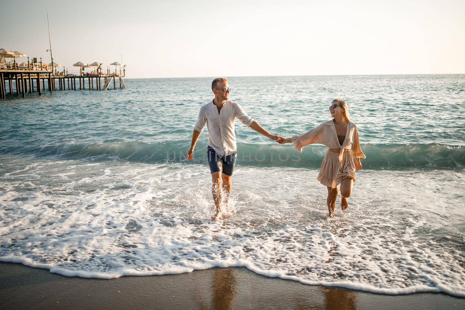 Happy couple by the sea. Honeymoon lovers. Man and woman on the island. Beautiful couple having fun on the seashore. Happy couple on vacation. Man and woman by the sea. by Dmitrytph