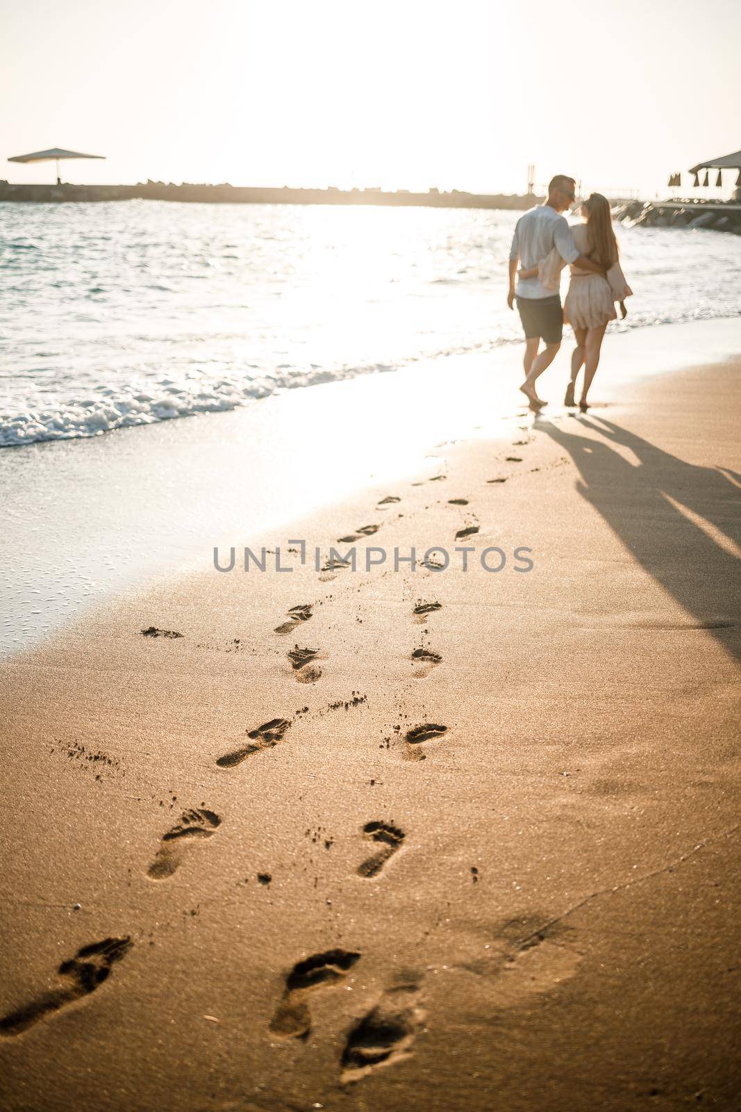 Summer holidays and travel. Sexy woman and man in sea water at sunset. Loving couple relax on the sunrise beach. Love relationship of a couple enjoying a summer day together. Selective focus by Dmitrytph