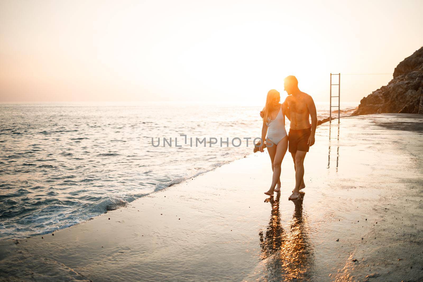 Romantic young couple in love walking together at sunset along the Mediterranean beach. Summer vacation in a warm country. Happy married couple on vacation in Turkey. Selective focus