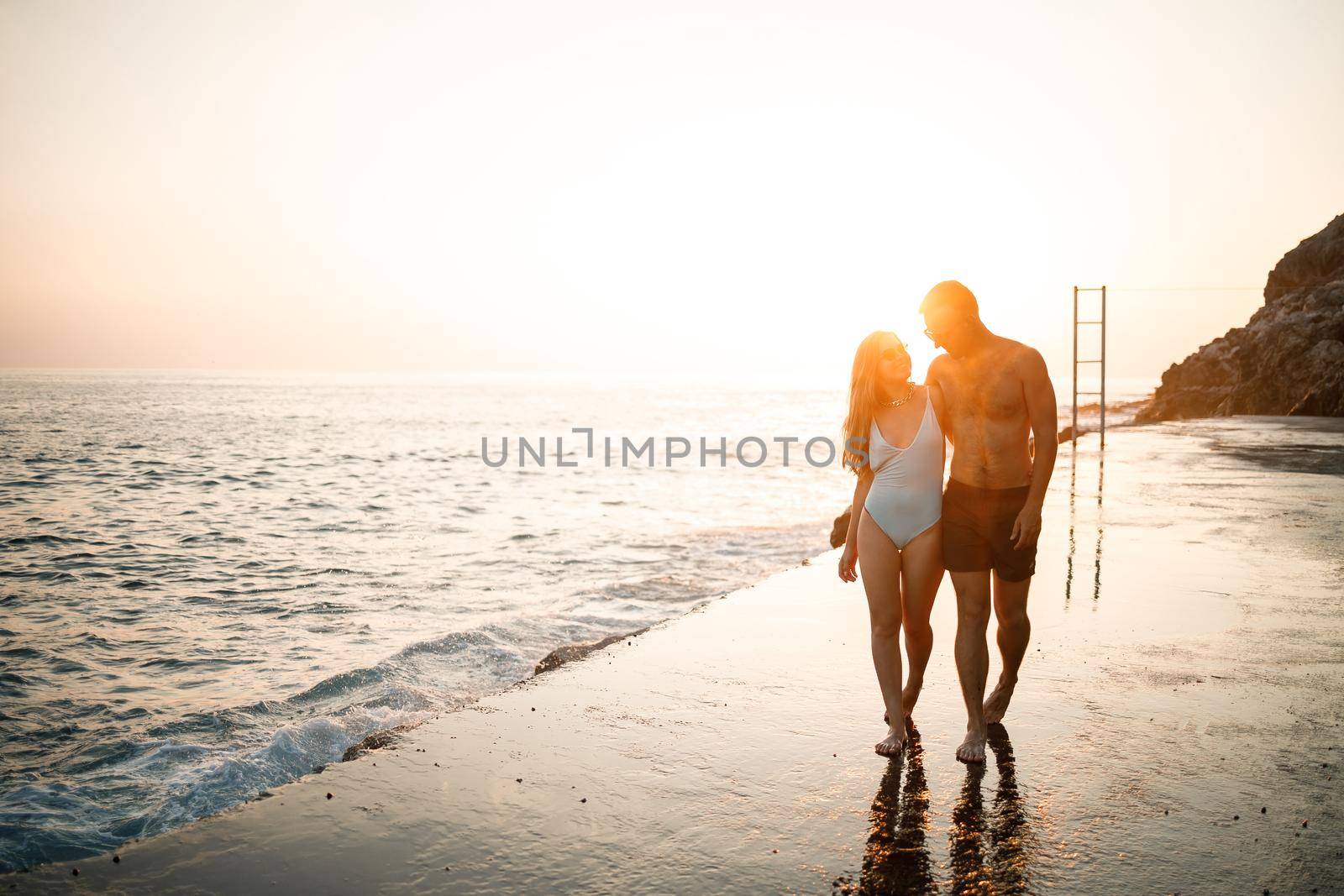 Romantic young couple in love walking together at sunset along the Mediterranean beach. Summer vacation in a warm country. Happy married couple on vacation in Turkey. Selective focus