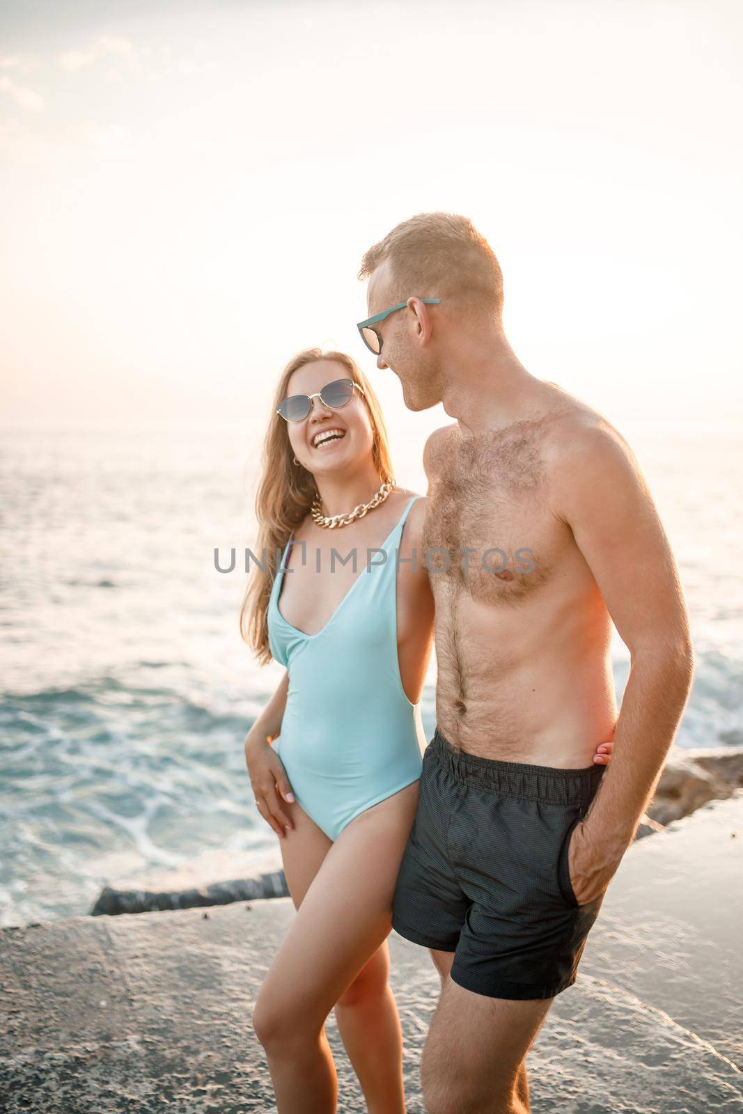 Romantic young couple in love walking together at sunset along the Mediterranean beach. Summer vacation in a warm country. Happy married couple on vacation in Turkey. Selective focus by Dmitrytph