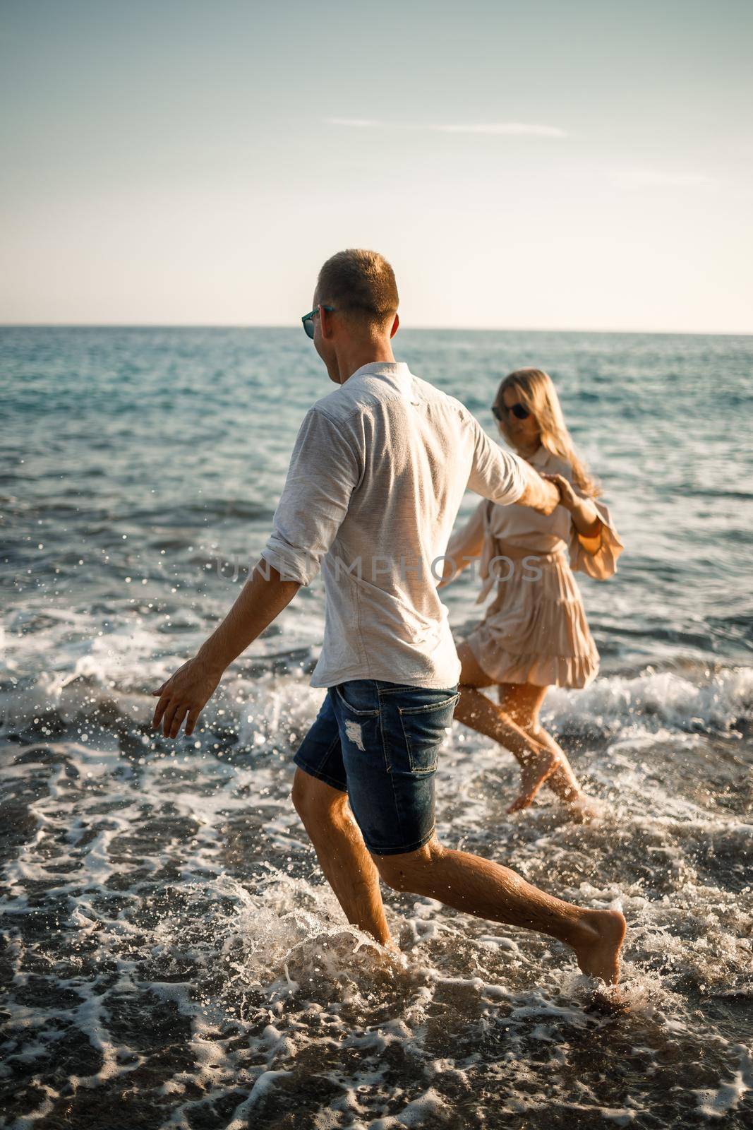 romantic young couple in love together on the sand walks along the beach of the Mediterranean sea. Summer vacation in a warm country. Selective focus