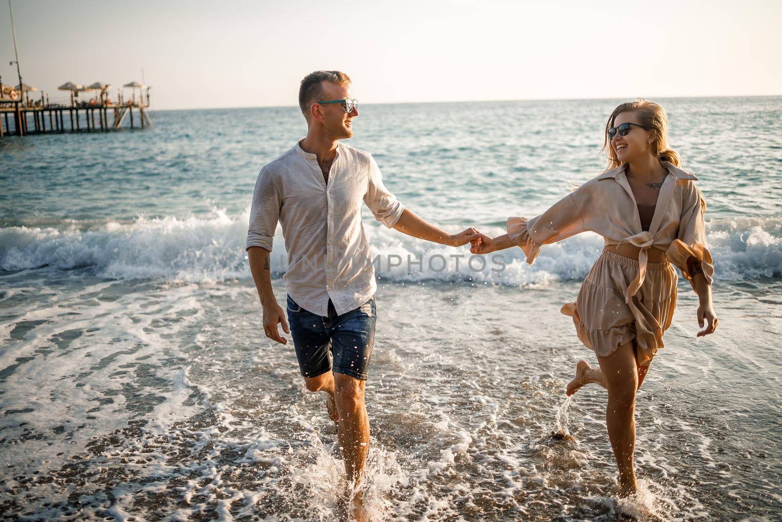 Happy couple by the sea. Honeymoon lovers. Man and woman on the island. Beautiful couple having fun on the seashore. Happy couple on vacation. Man and woman by the sea.