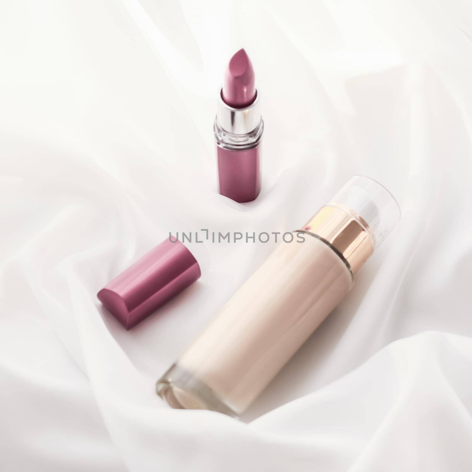 Beige tonal cream bottle make-up fluid foundation base and pink lipstick on silk background, cosmetics products as luxury beauty brand holiday design by Anneleven