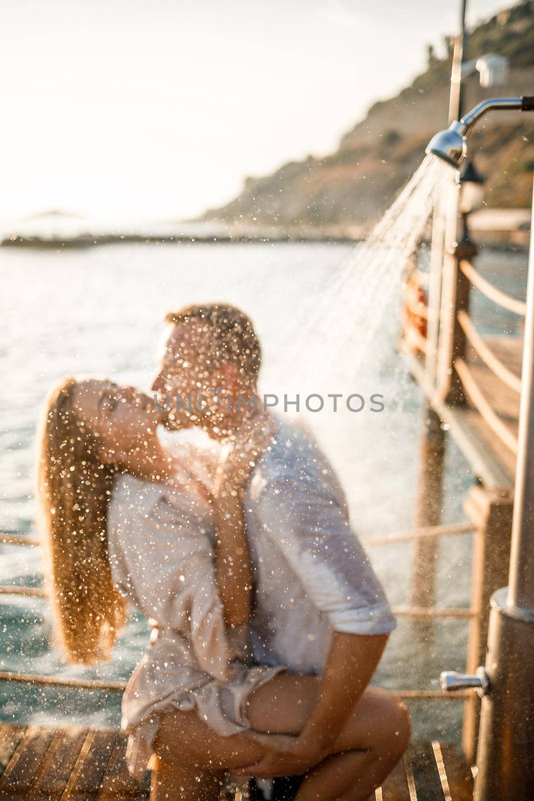 Happy couple by the sea. A guy and a girl are under the shower on an open-air pier. Happy couple on vacation. Man and woman by the sea. Selective focus by Dmitrytph