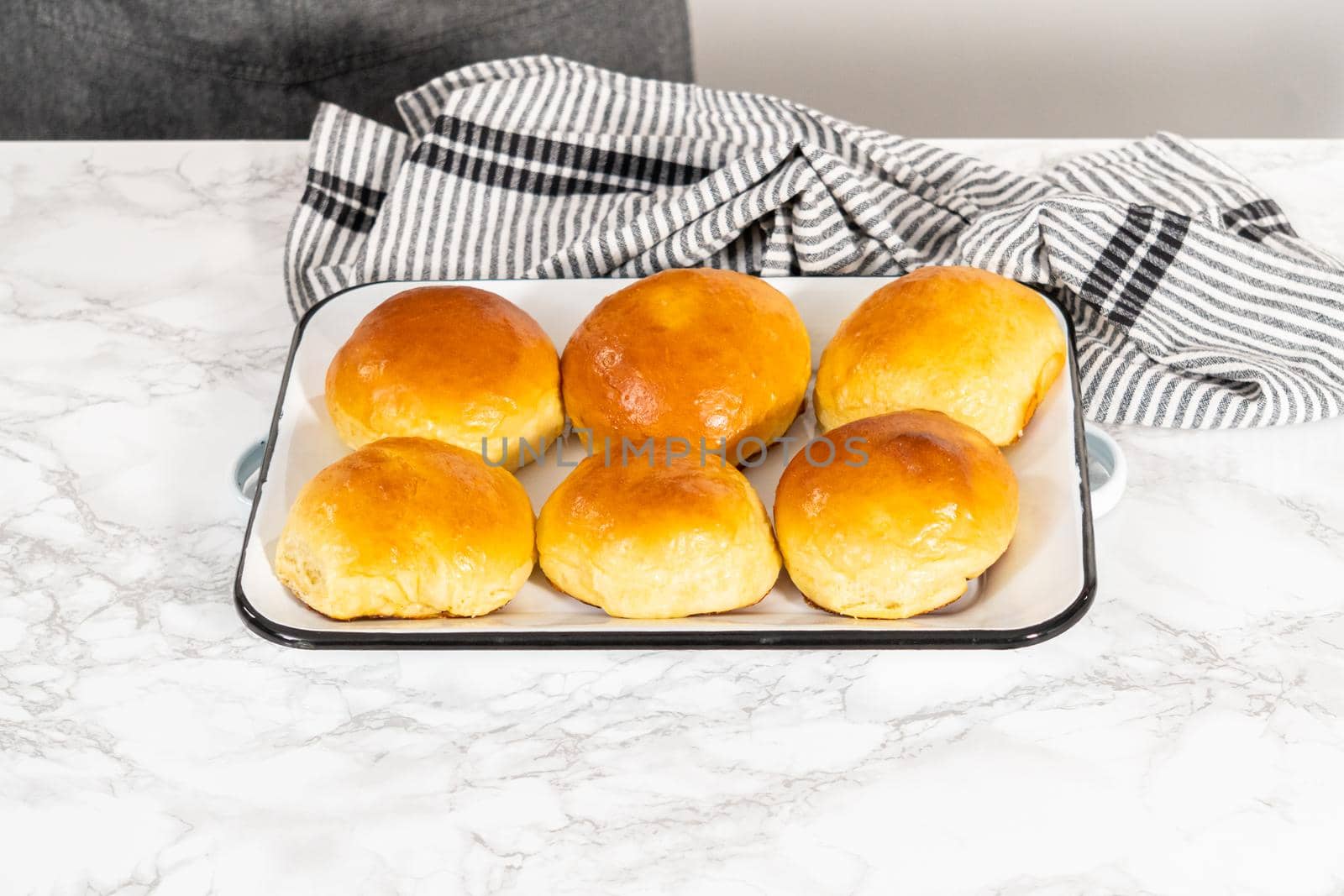 Freshly baked brioche buns on a metal serving tray.
