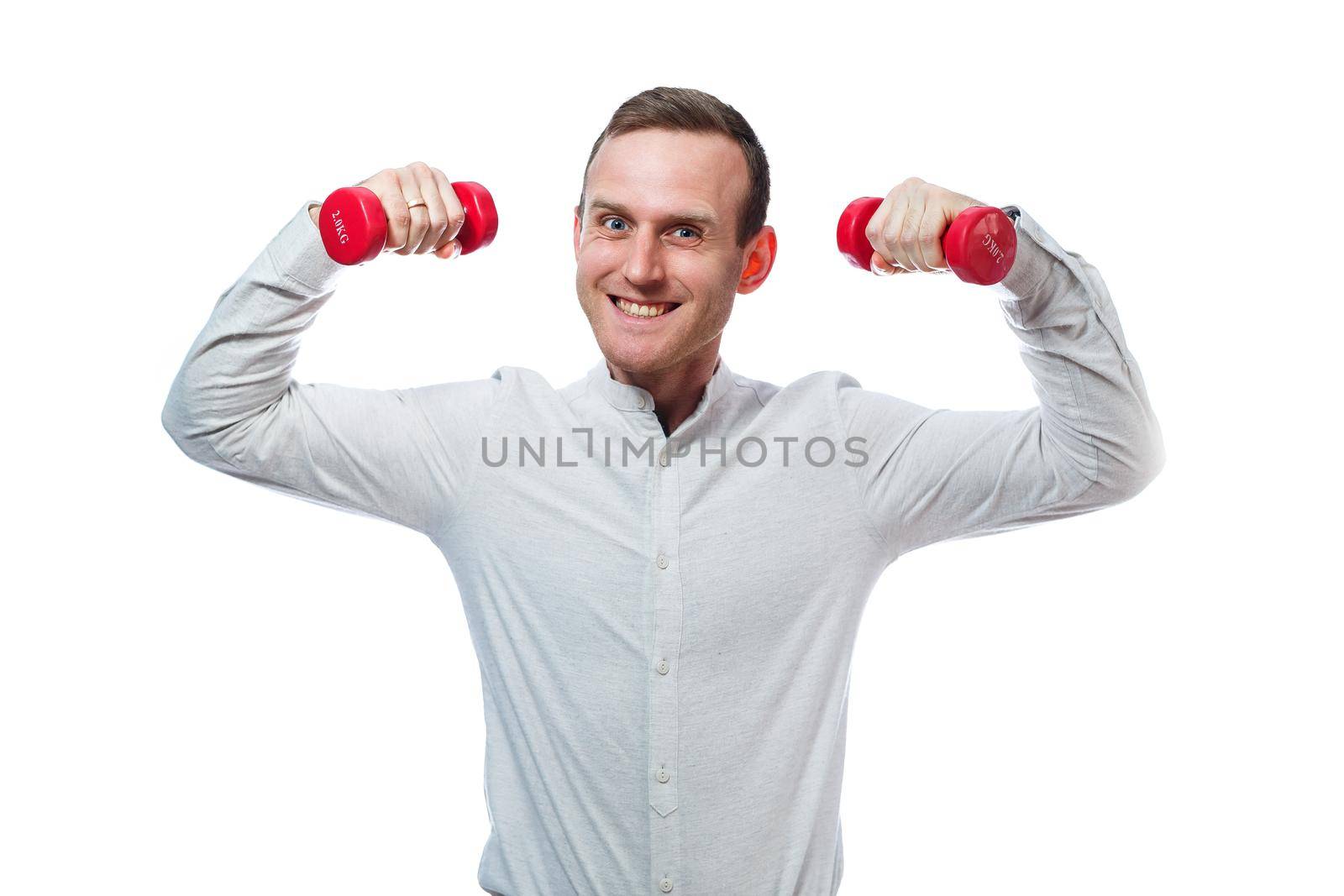 Caucasian man businessman, a teacher involved in sports. He is holding a red dumbbell. He is wearing a shirt. Emotional portrait. Isolated on white background by Dmitrytph