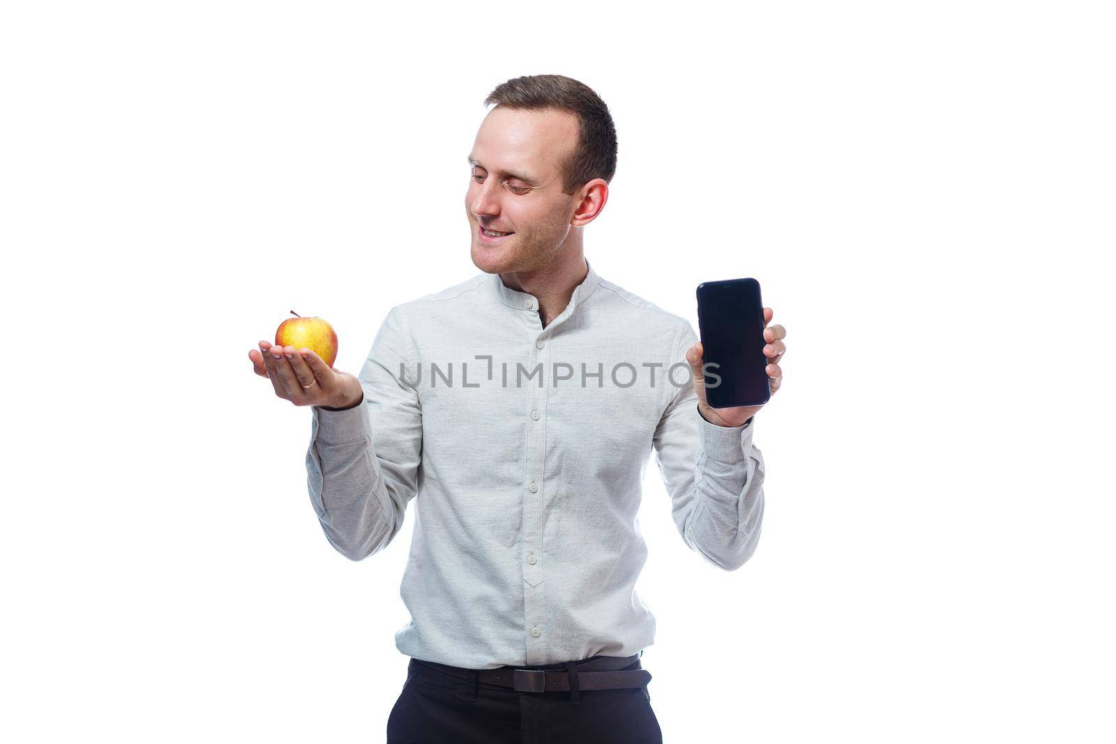 Caucasian male businessman holding a mobile phone in black and holding a red-yellow apple. He is wearing a shirt. Emotional portrait. Isolated on white background