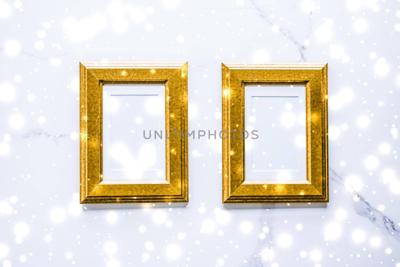 Golden photo frame and glowing glitter snow on marble flatlay background for Christmas and winter holidays by Anneleven