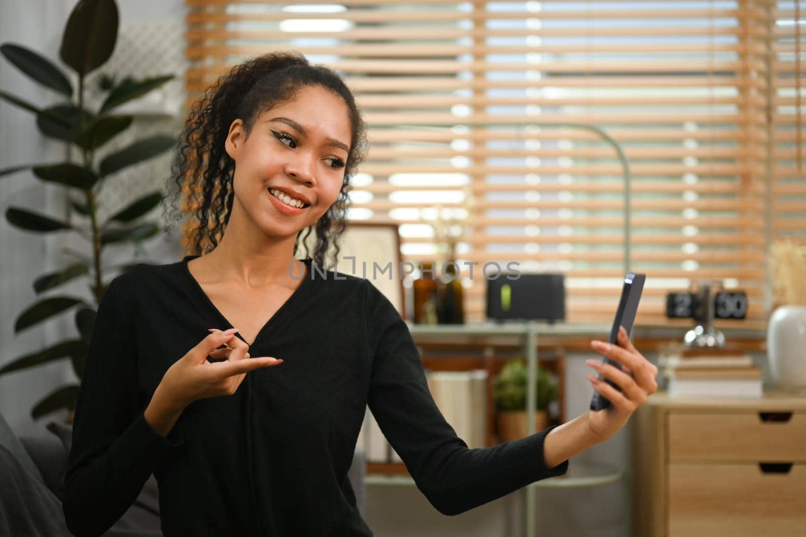 Attractive woman having a video call with her friends via mobile phone. People and communication concept.