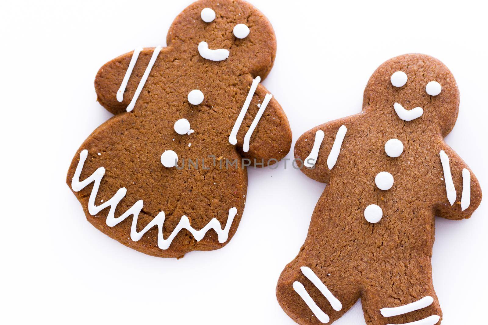 Homemade gingerbread cookies decorated with white icing on white background.