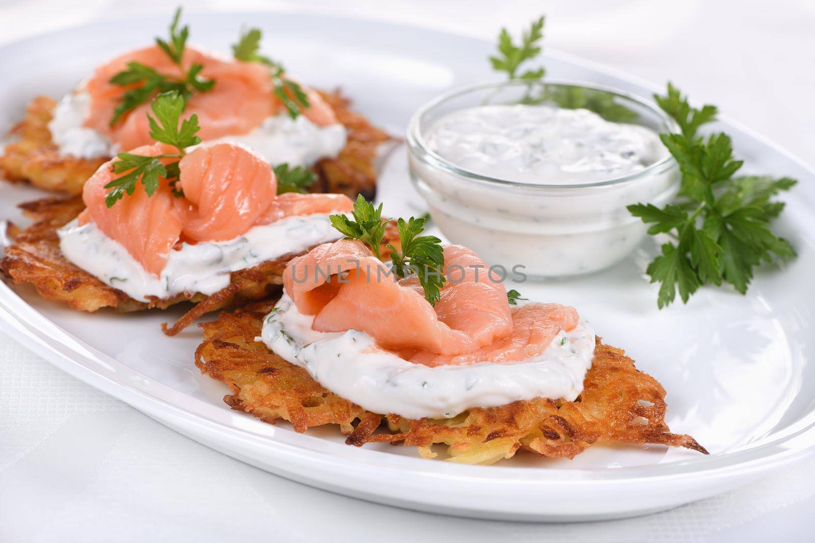 Crispy Potato fritters (a pancake, especially one made with grated potato) with cream cheese sauce with herbs and salmon