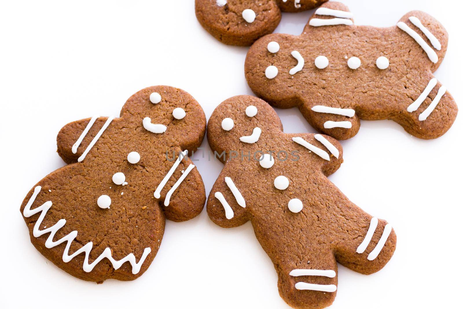 Homemade gingerbread cookies decorated with white icing on white background.