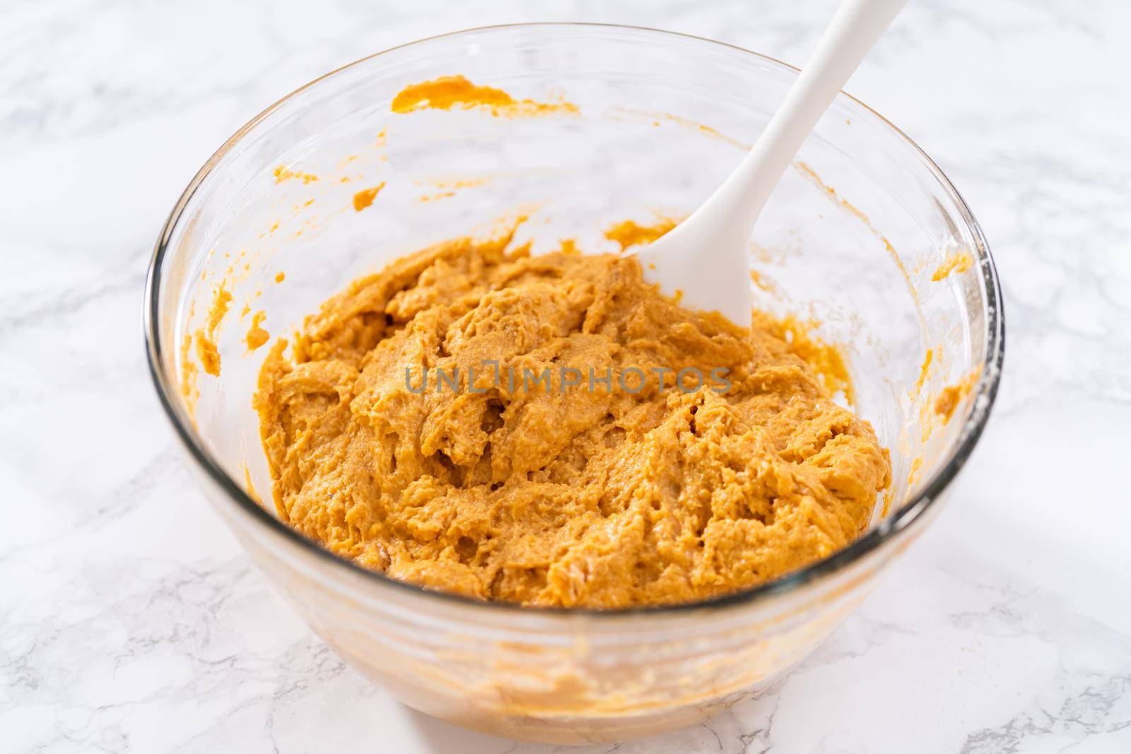 Mixing ingredients in a large glass mixing bowl to bake chocolate pumpkin bundt cake with toffee glaze.