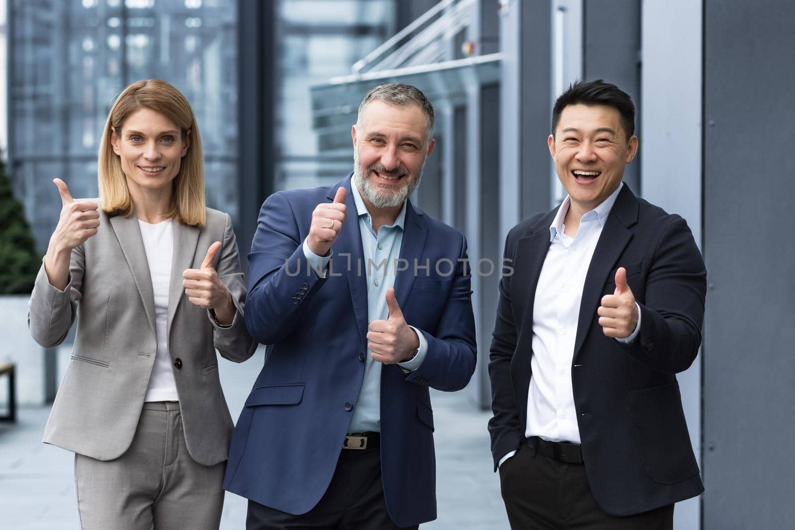 Cheerful dream team, senior and experienced IT professionals in business suits smiling and happy holding thumb up and looking at camera, diverse group of project managers outside office building.