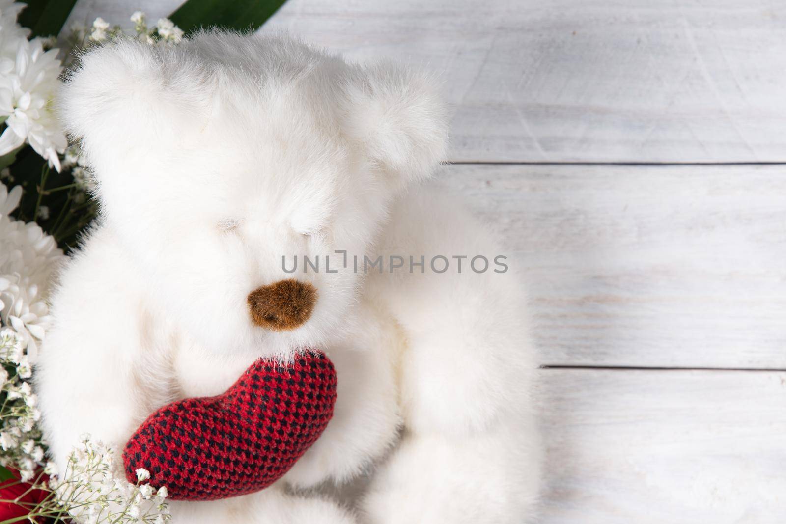 Valentine's day gift, teddy bear with a heart, a box of pralines and a bouquet of flowers on the bed early in the morning. High quality photo