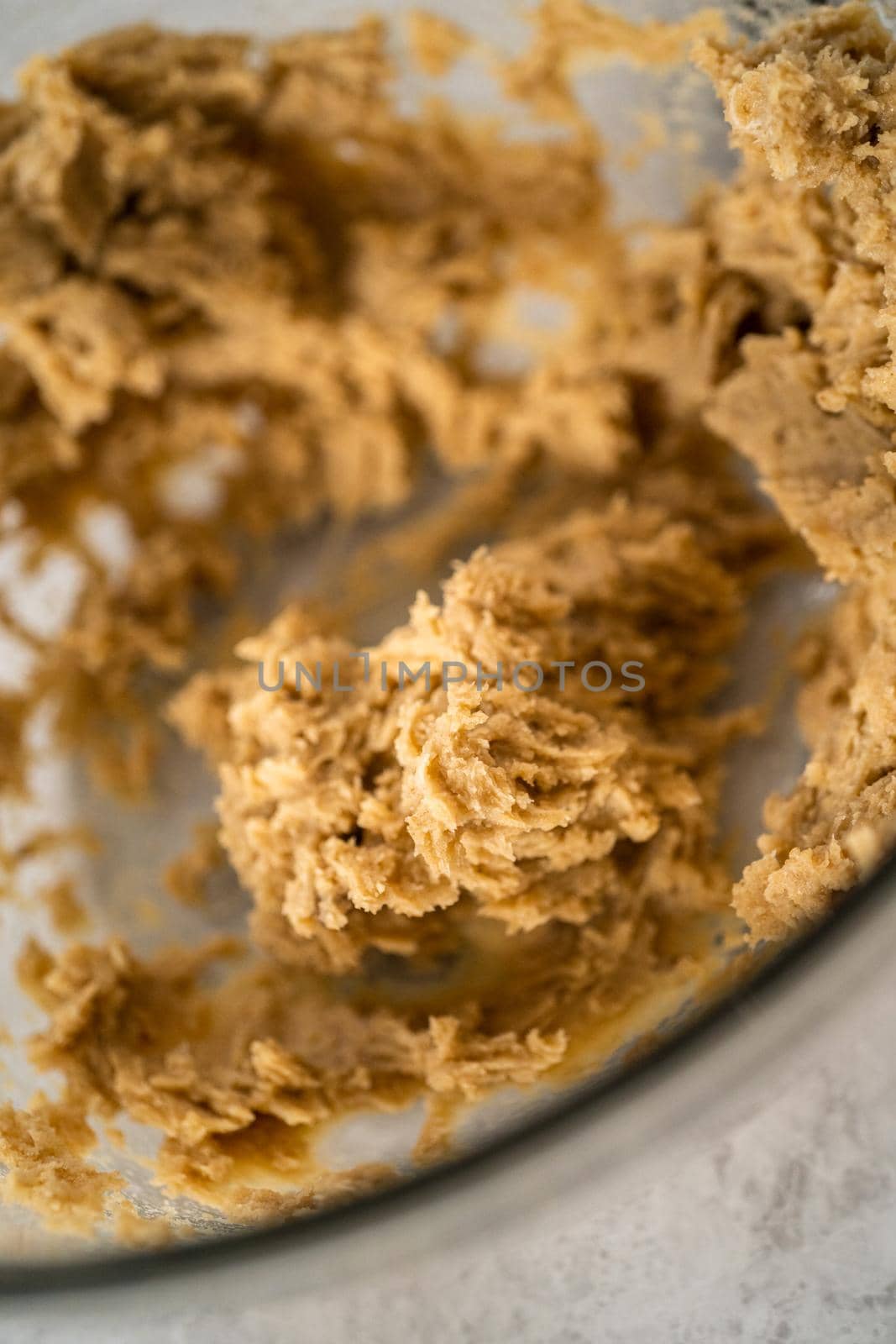 Mixing ingredients in a large glass mixing bowl with a kitchen mixer to bake chocolate cookies with peppermint chips.