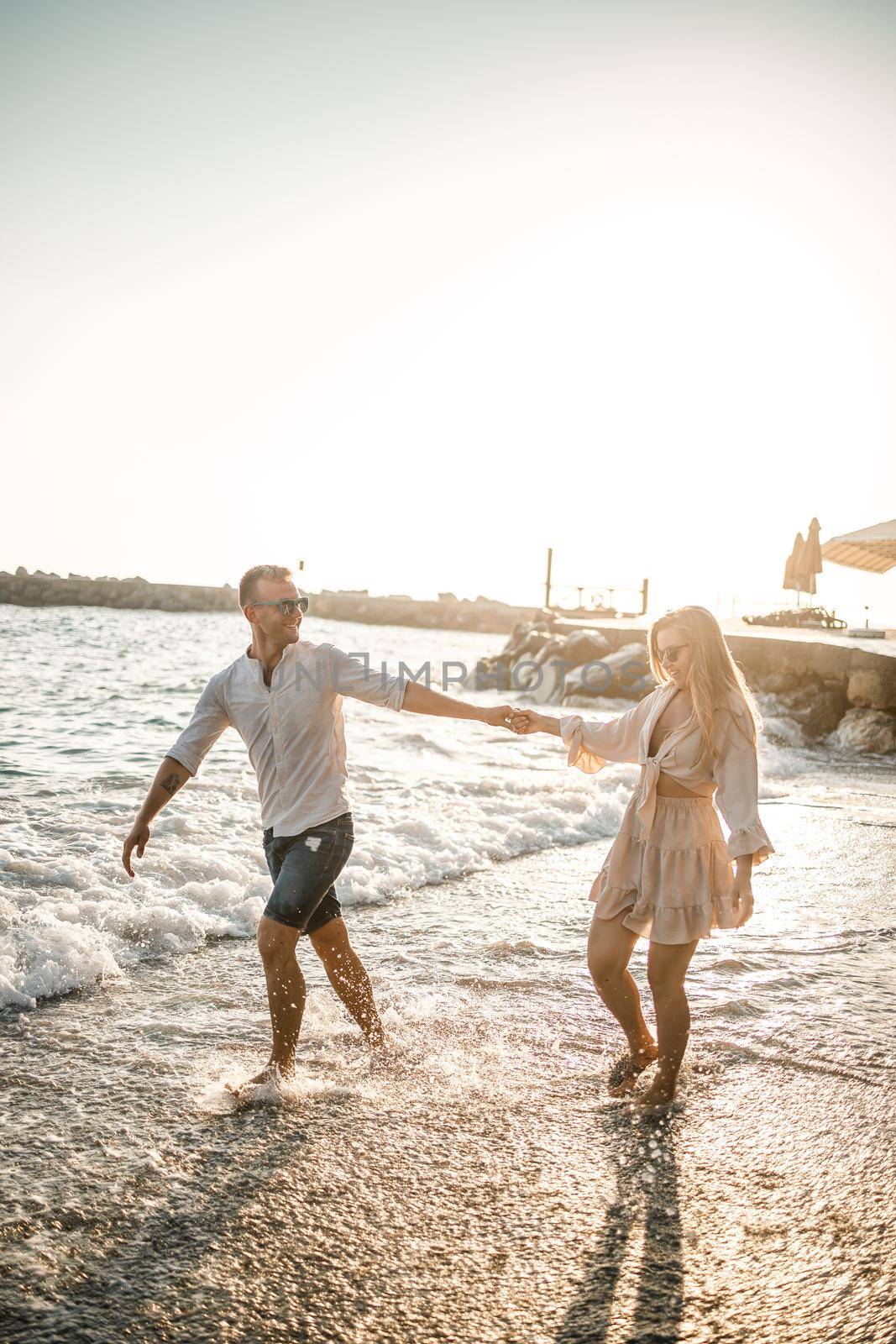 Summer holidays and travel. Sexy woman and man in sea water at sunset. Loving couple relax on the sunrise beach. Love relationship of a couple enjoying a summer day together