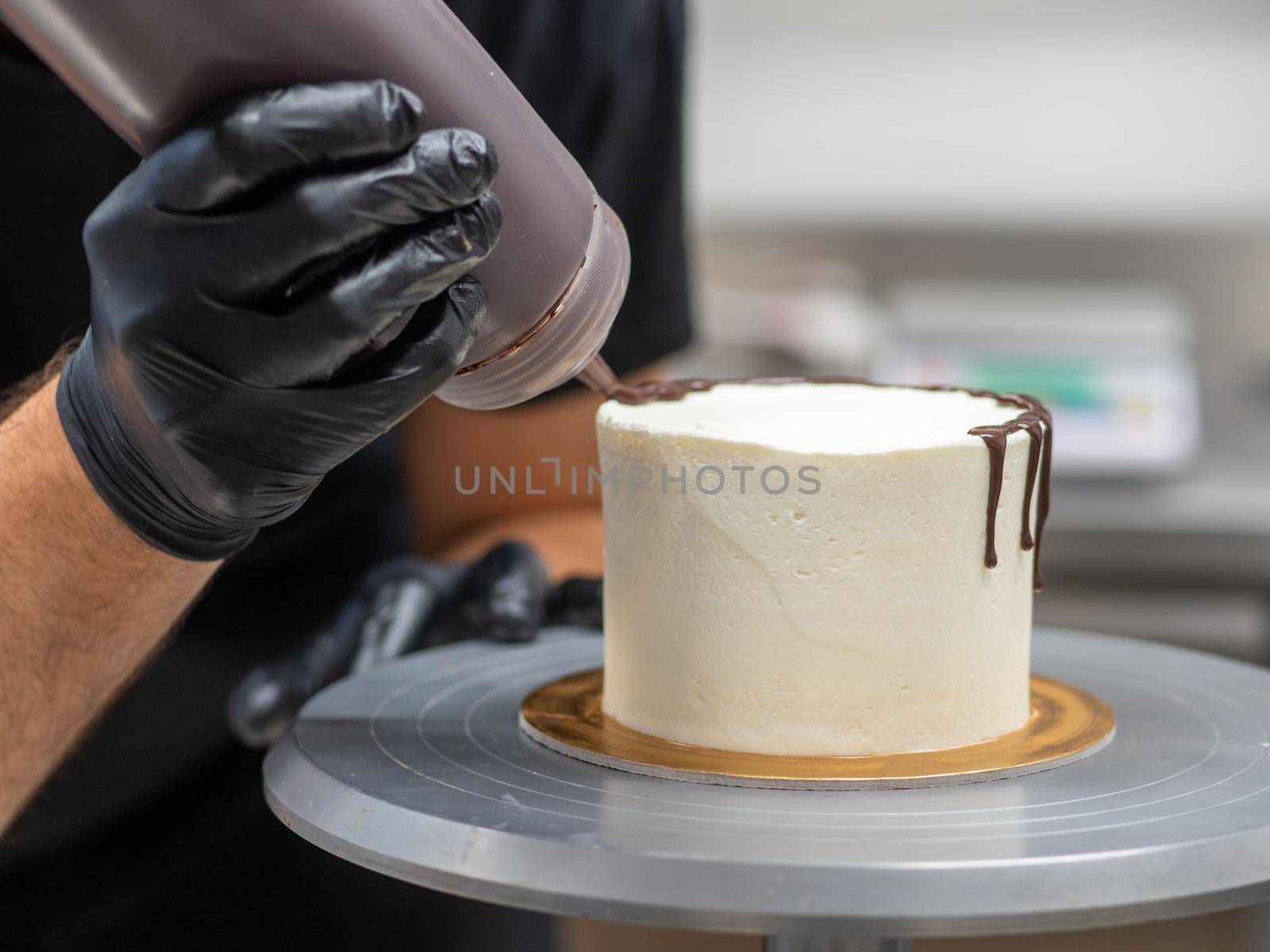 unrecognizable worker preparing a sweet dripping choco cake and berries