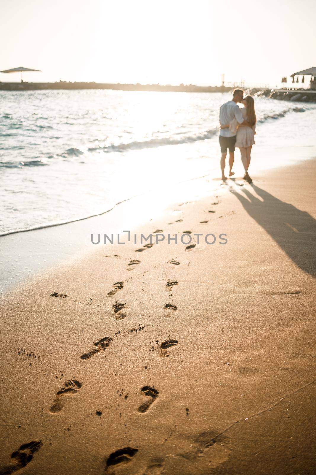 Summer holidays and travel. Sexy woman and man in sea water at sunset. Loving couple relax on the sunrise beach. Love relationship of a couple enjoying a summer day together. Selective focus by Dmitrytph