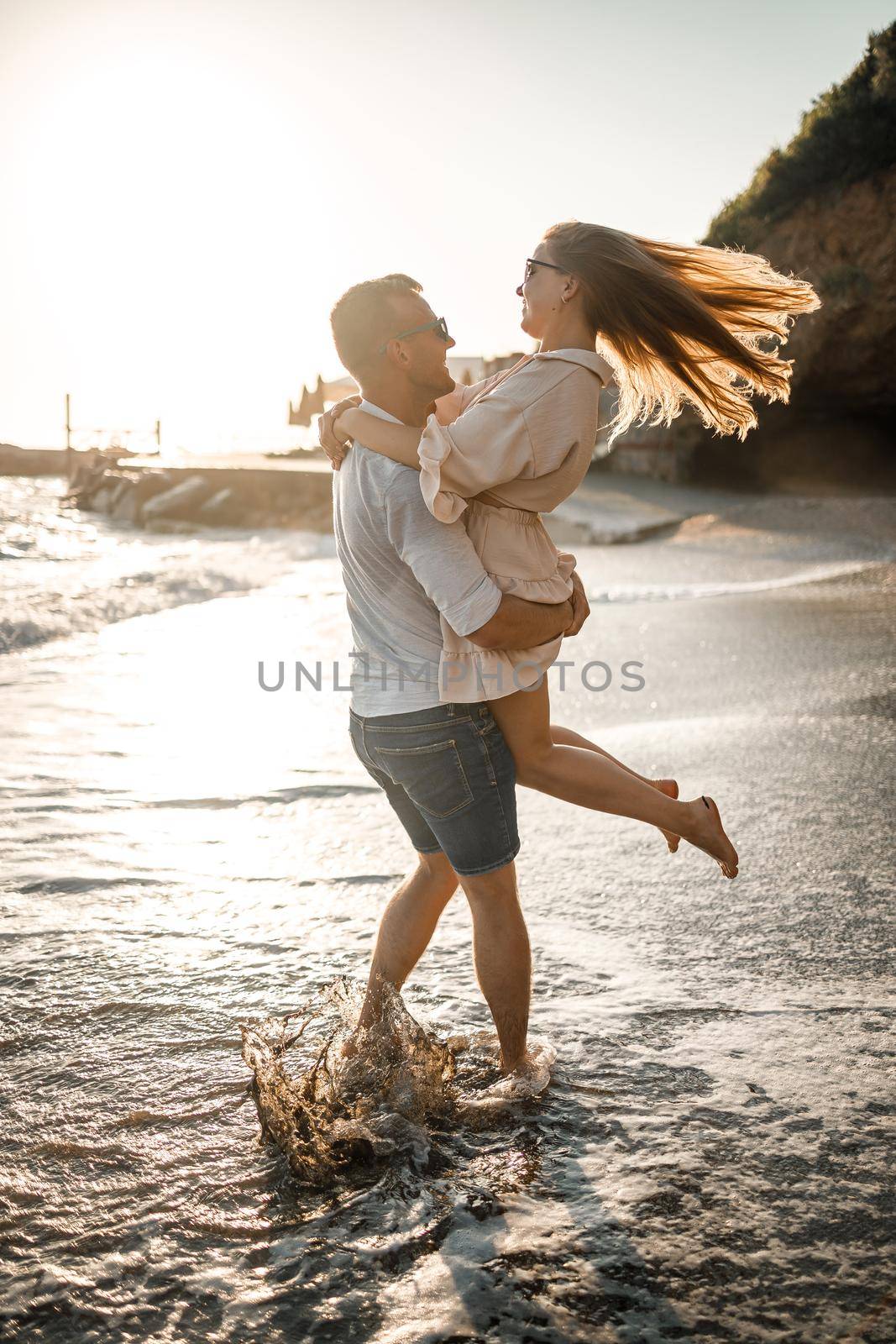 A couple in love is walking on the beach near the sea. Young family at sunset by the mediterranean sea. Summer vacation concept