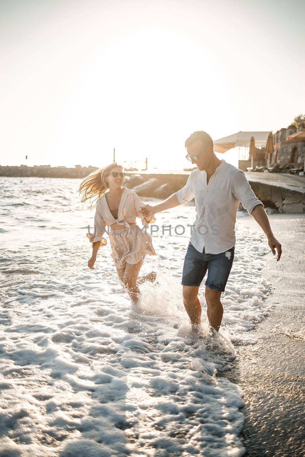 A couple in love is walking on the beach near the sea. Young family at sunset by the mediterranean sea. Summer vacation concept by Dmitrytph