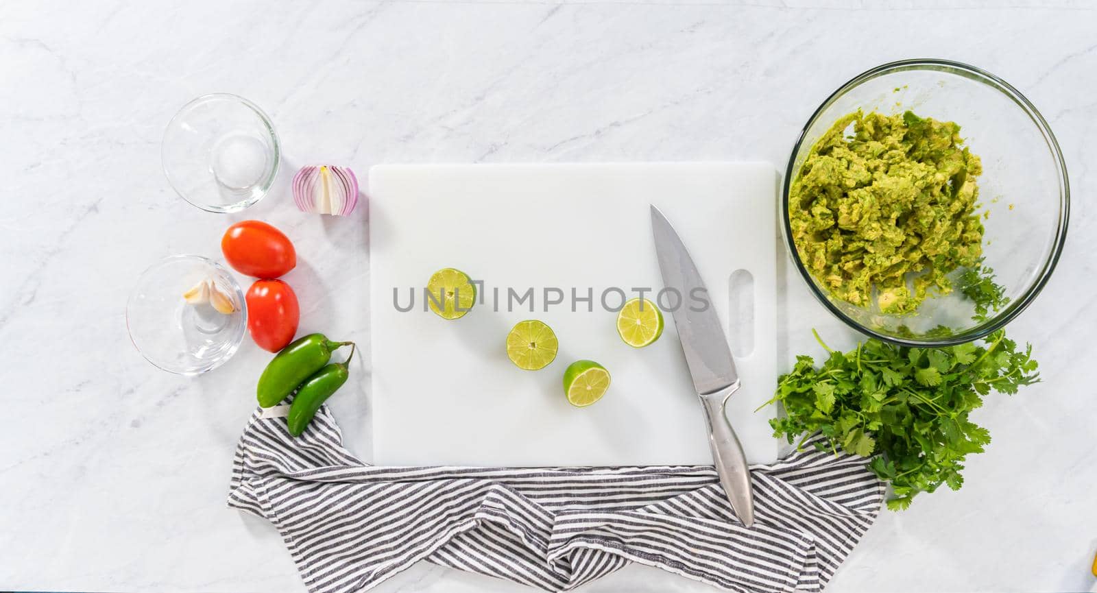 Flat lay. Cutting ingredients on a white cutting board to make classic guacamole dip.