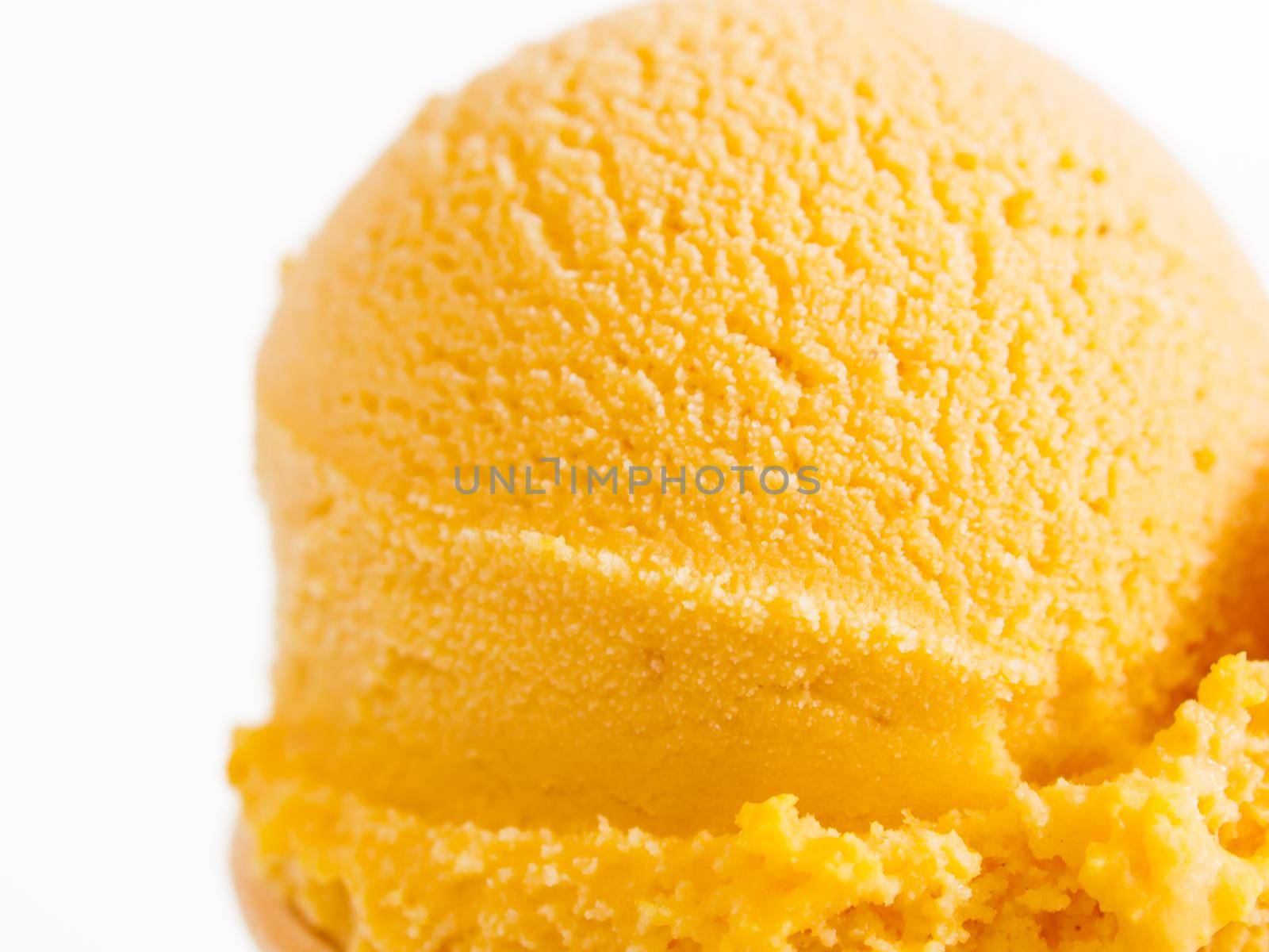 Scoop of gourmet pumpkin gelato in cake cone on white background.