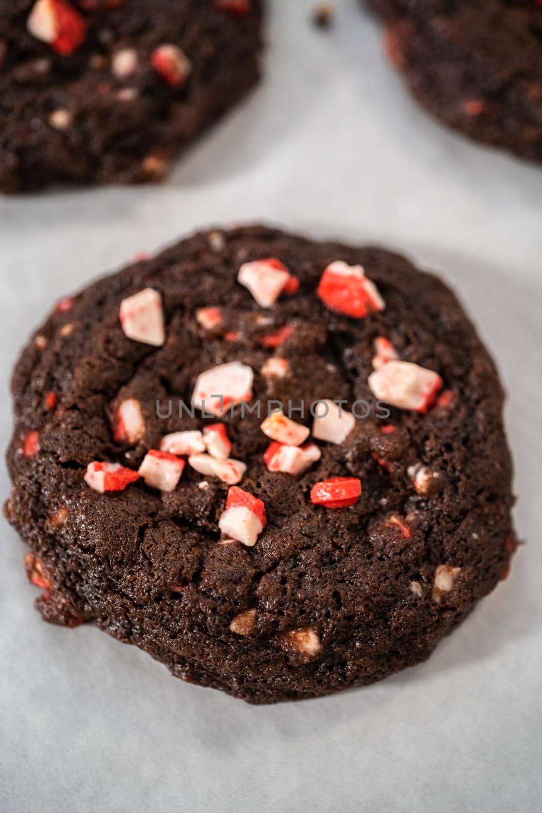 Cooling freshly baked chocolate cookies with peppermint chips on a kitchen counter.