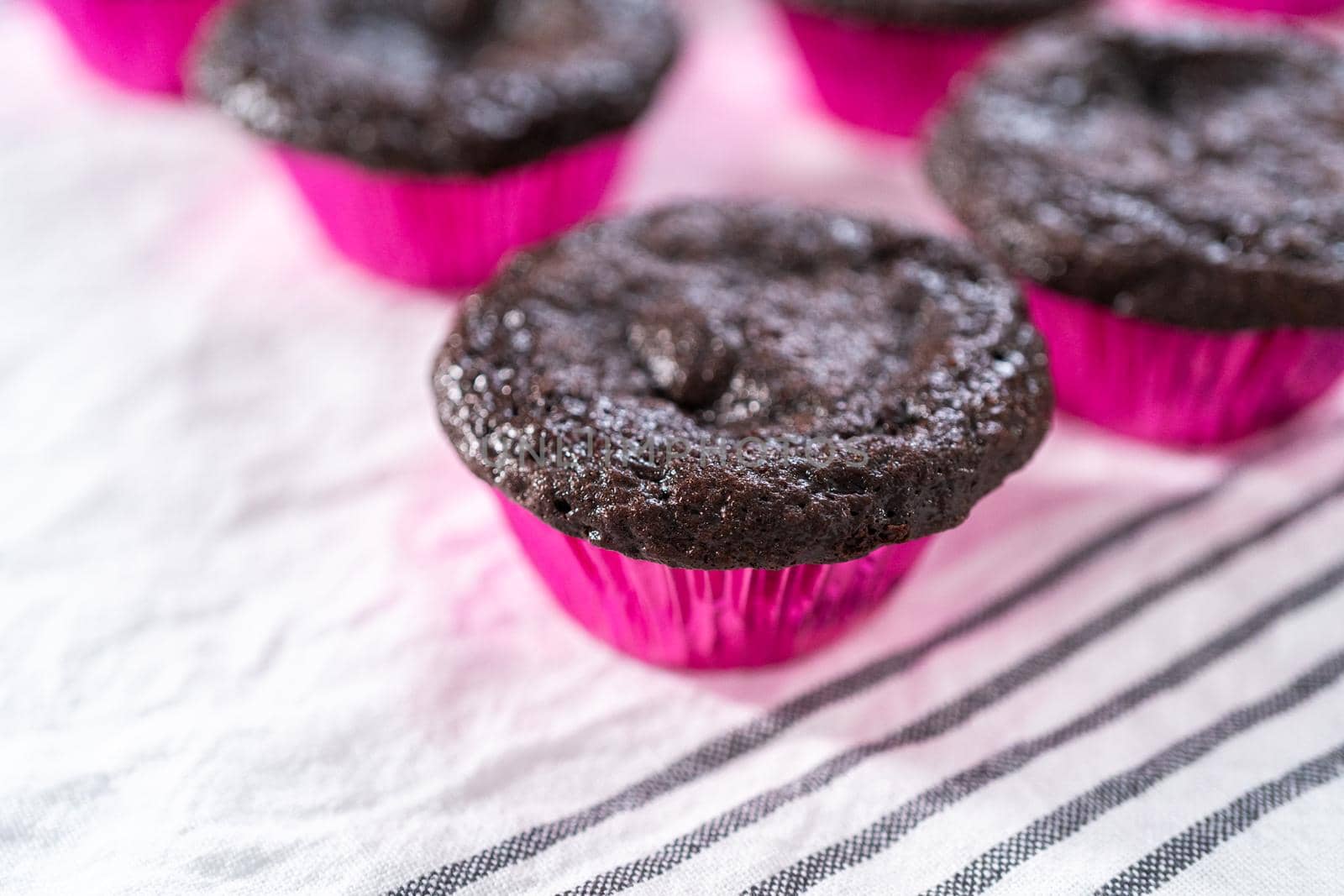 Cooling freshly baked chocolate cupcakes on a paper towel.