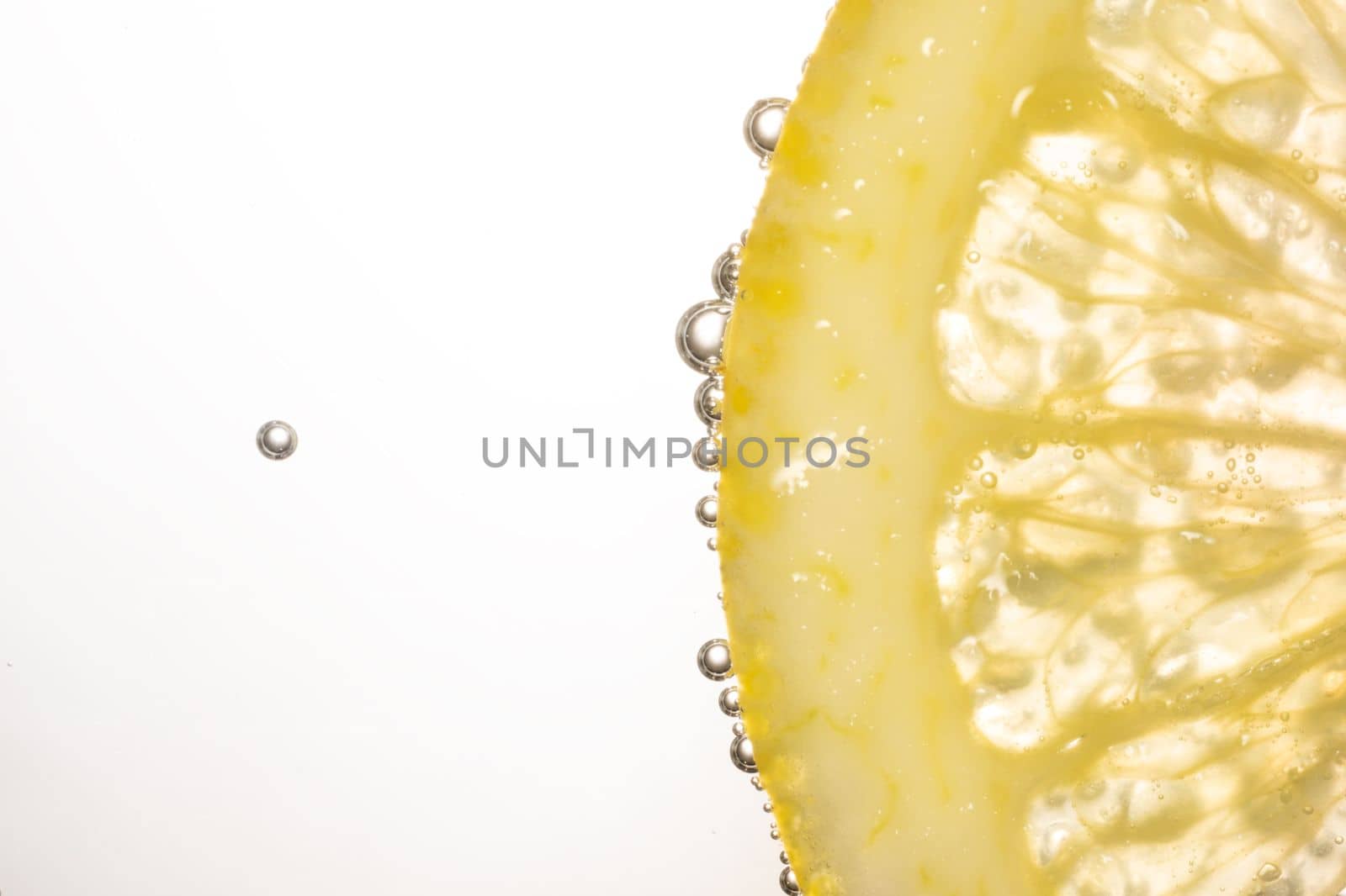 Macro photo of lemon slice In water with bubbles isolated on white background. Freshness and healthy lifestyle concept. High quality photo