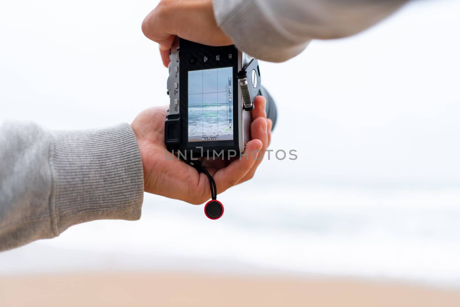 Traveller make photo using mirrorless camera in hand, travel blogger, Close up of mens hands holding mirrorless camera taking picture at ocean view