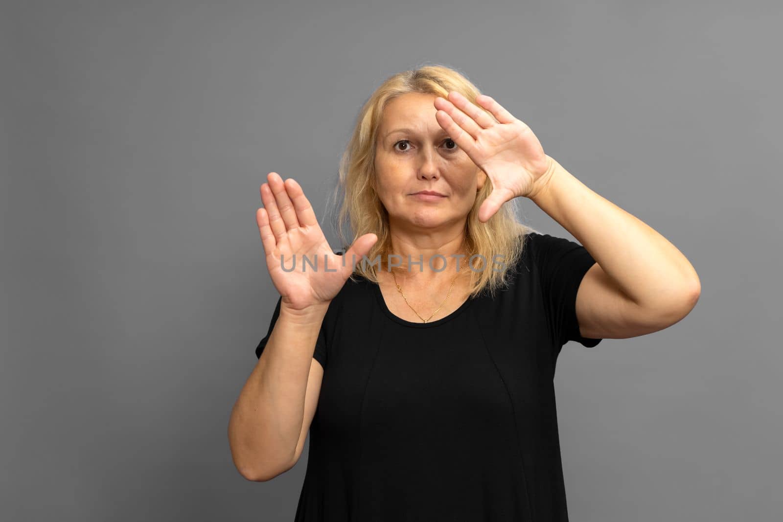 Beautiful blonde Caucasian woman holds her hands in front of her with open palms facing the camera. advertising concept of business leader woman.