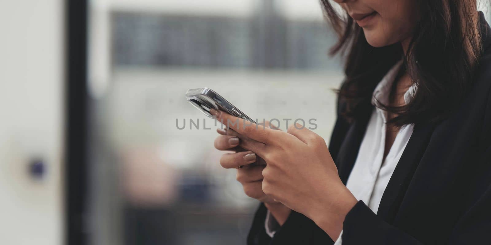 Closeup of female hands using modern smartphone device near urban office, focus on cellphone, social network and communication concept