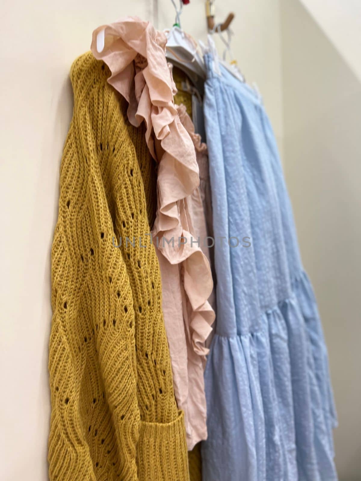 Close up of Clothes in blue, ochre and pink colour hanging on a hook. by Varaksina