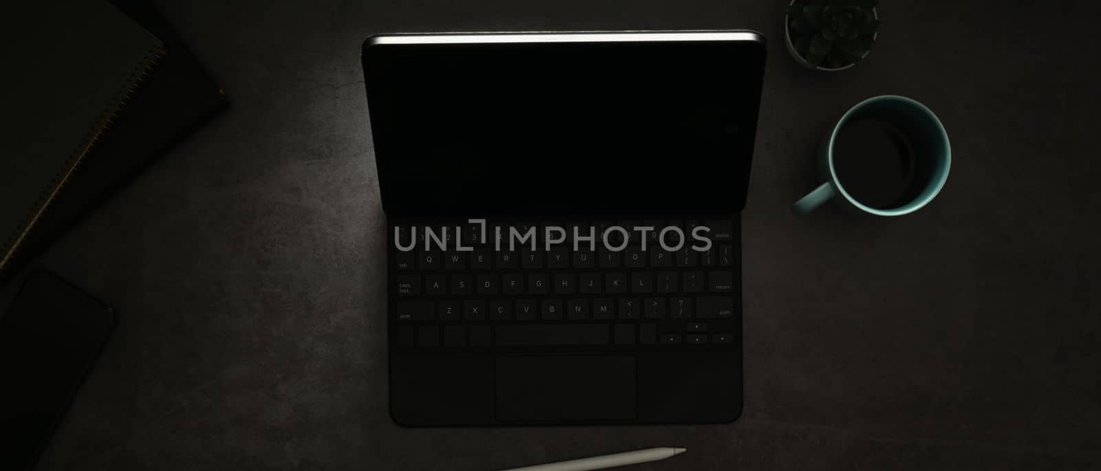 Digital tablet with wireless keyboard and cup of coffee on black wooden table by prathanchorruangsak