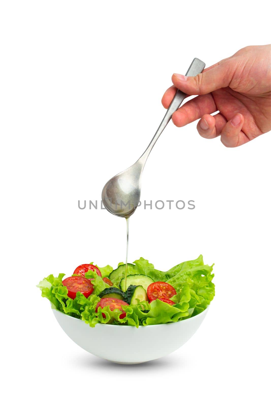 Bowl of salad and male hand pouring oil with spoon over salad isolated by its_al_dente
