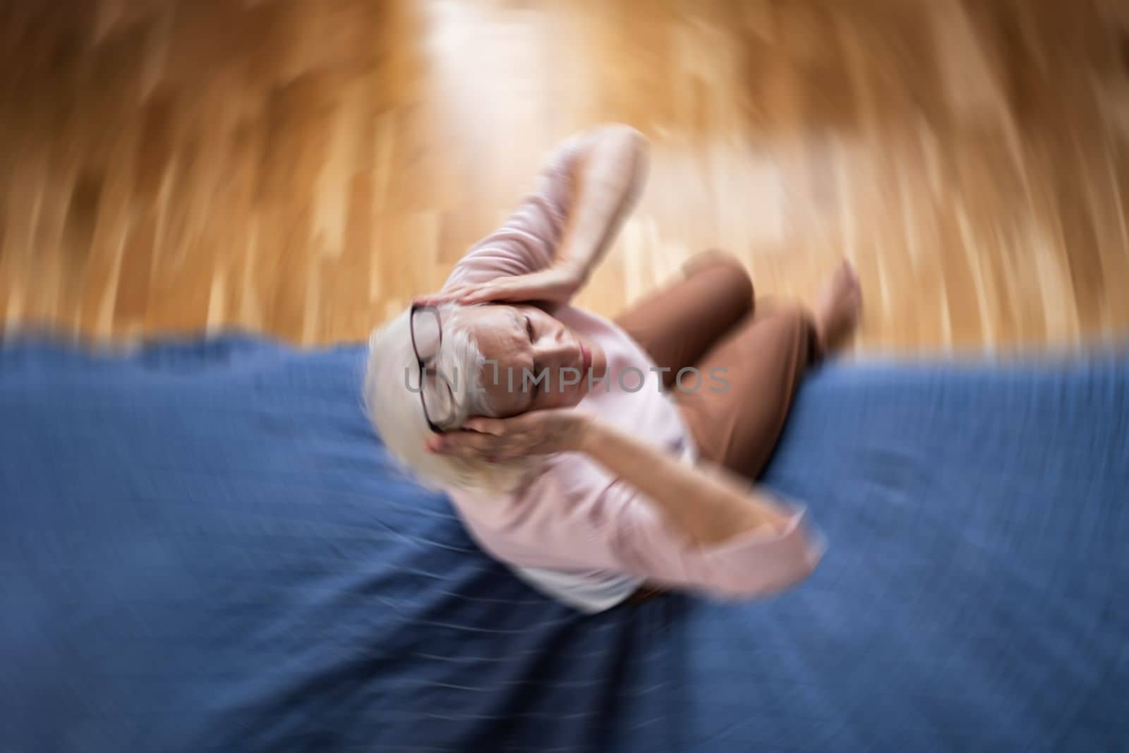 Senior caucasian woman suffering from a headache resting at home on sofa