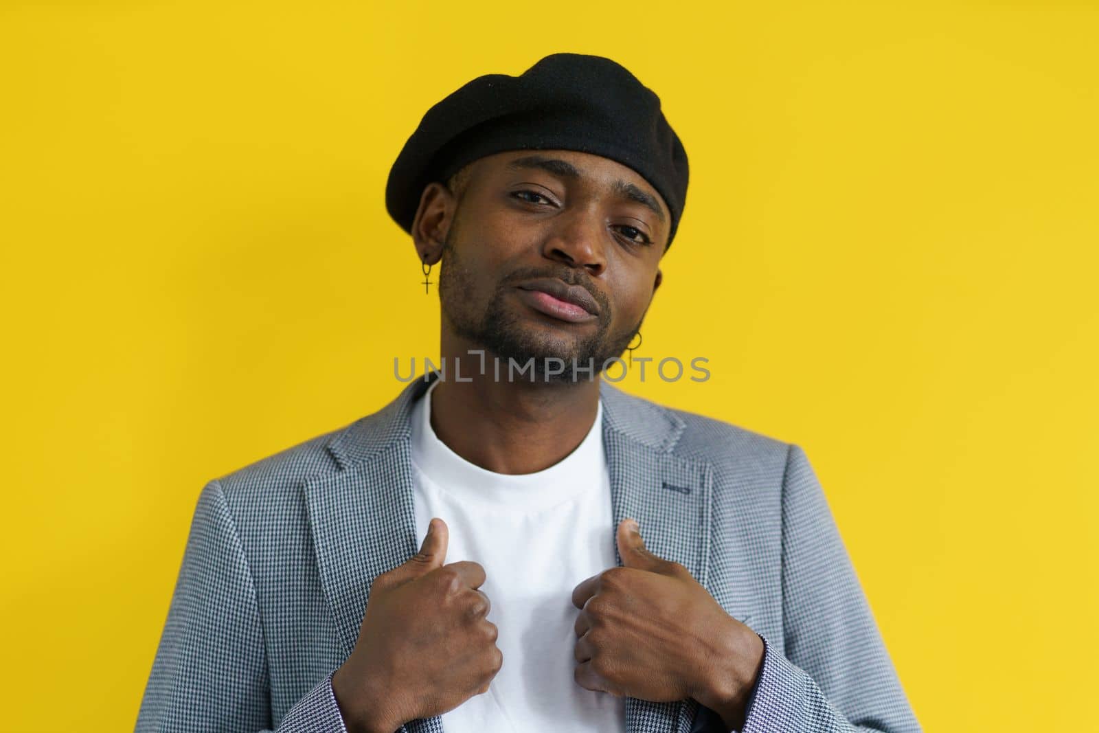 Young african gangster in beret and suit looking in camera with call. by LipikStockMedia