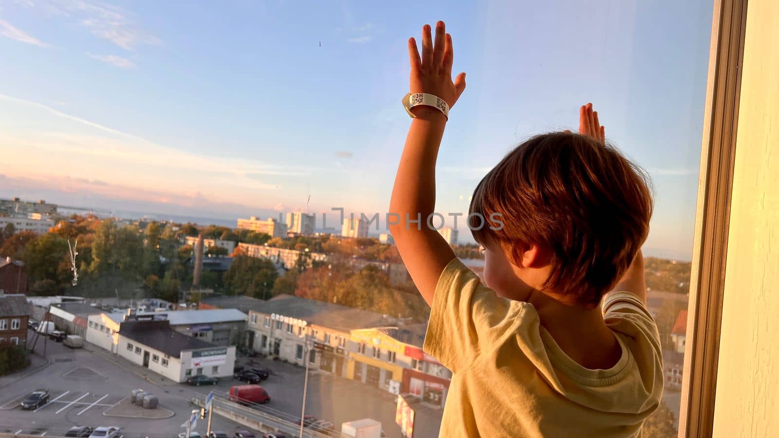 Pre-school boy looking out of the window of a skyscraper by Varaksina