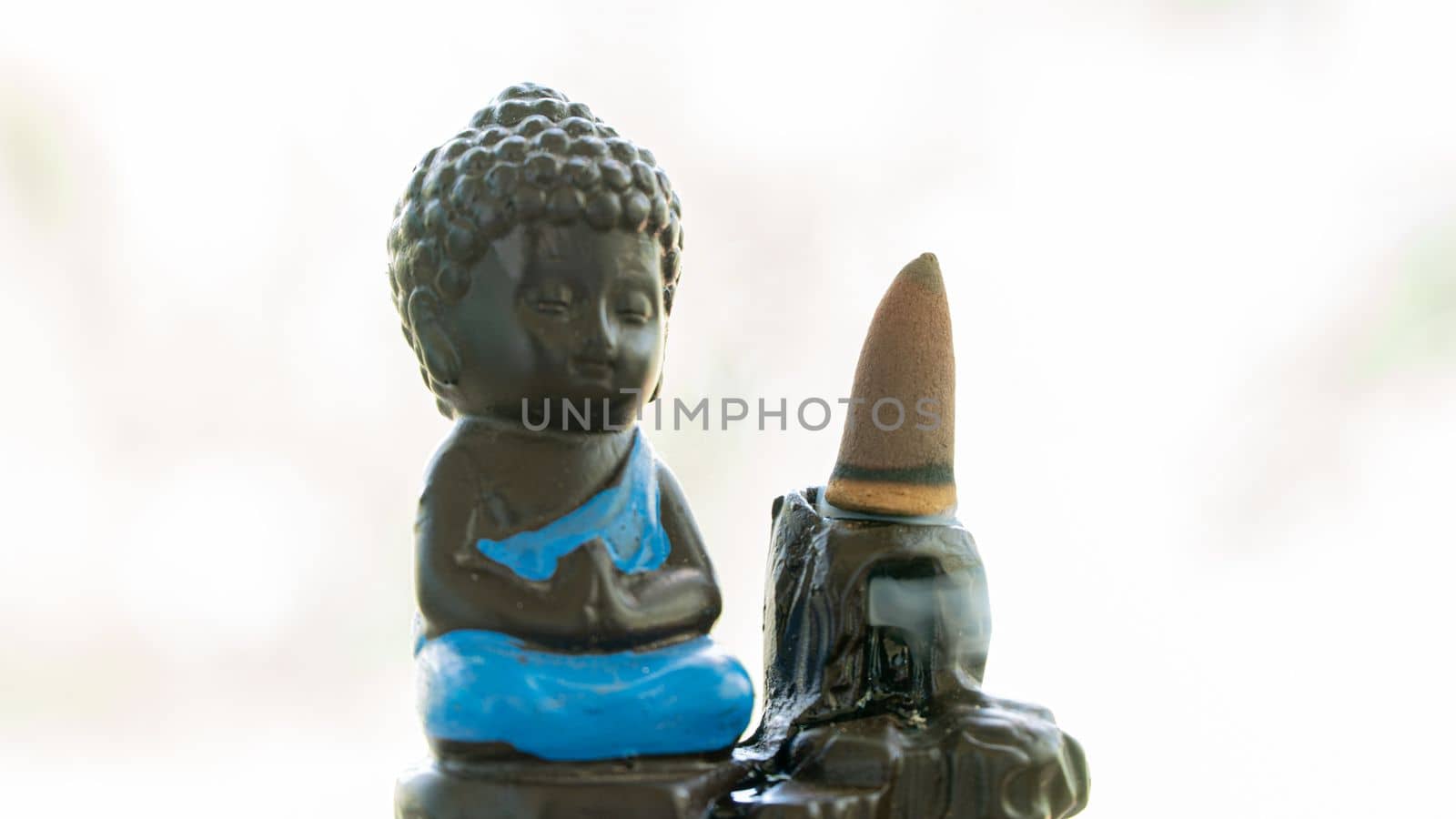 statuette of meditating buddha with incense cone, aromatherapy, meditation. High quality photo