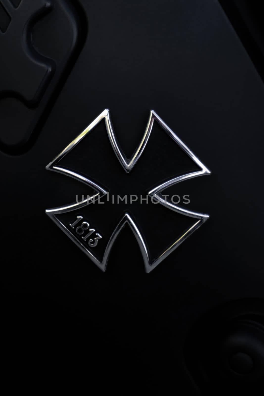 Metallic black German Maltese cross on the black matte tank of the motorcycle close up