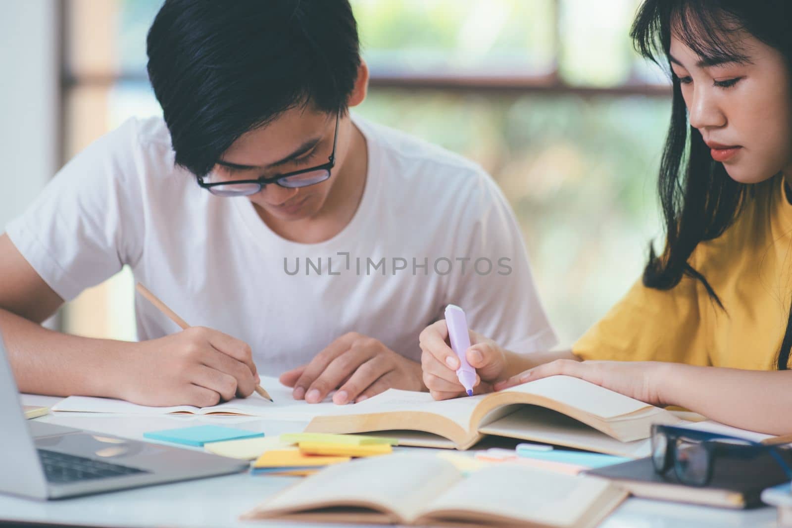 Young woman and man studying for a test or an exam. Tutor books with friends. Young students campus helps friend catching up and learning.