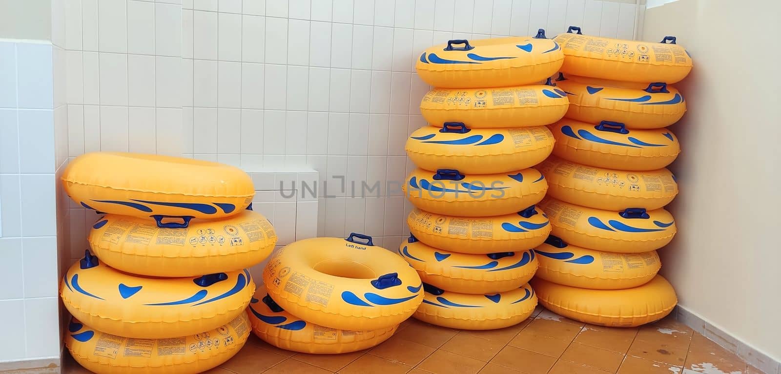 Stacks of yellow water tubes, lying near a light tiled wall.